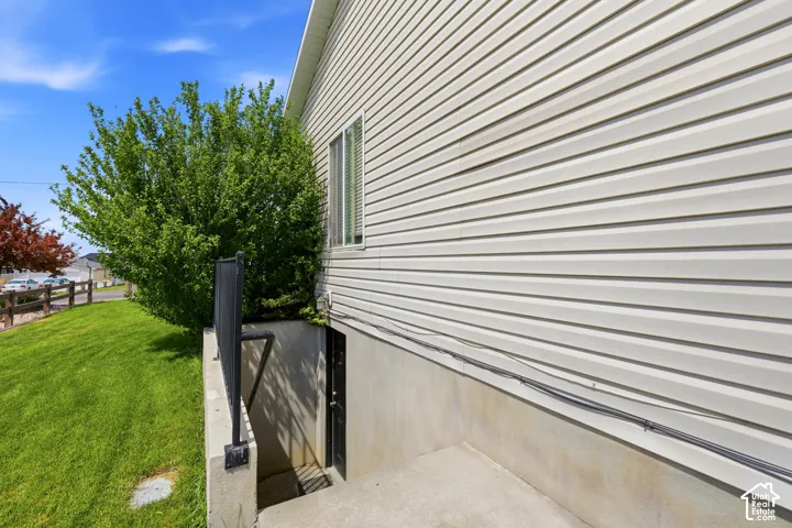 Side exterior featuring horizontal vinyl siding, a basement entrance with concrete stairs, and a black metal railing