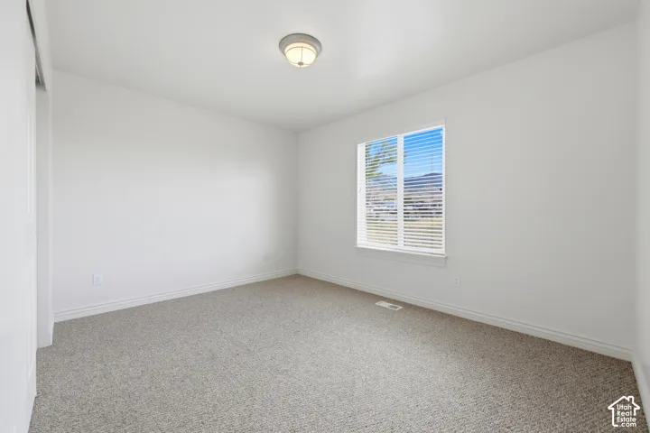 Spacious room featuring neutral carpeting and white baseboards