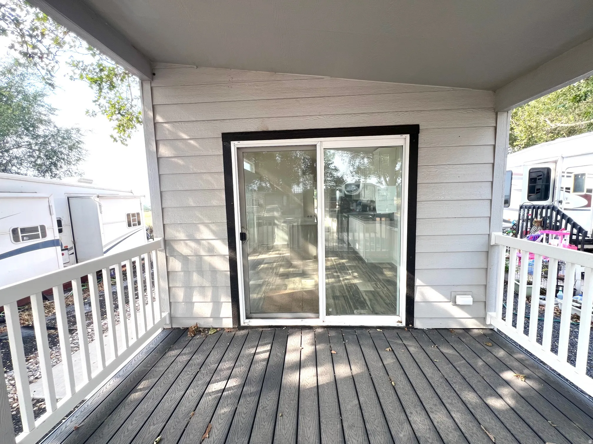Covered porch featuring durable composite decking, white railing system, and light-colored siding