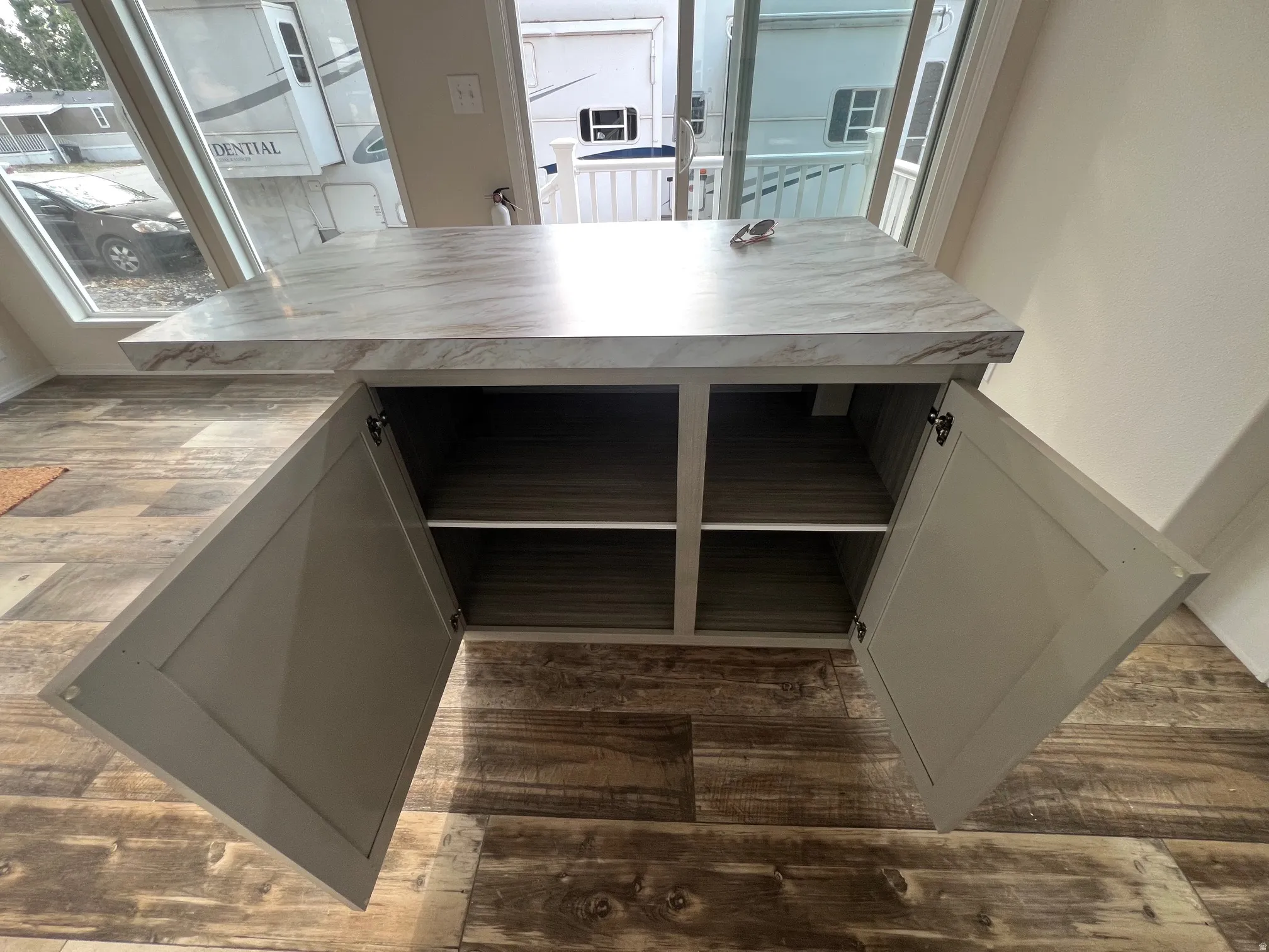 Built-in cabinetry featuring a marble-look countertop and wood-finish flooring