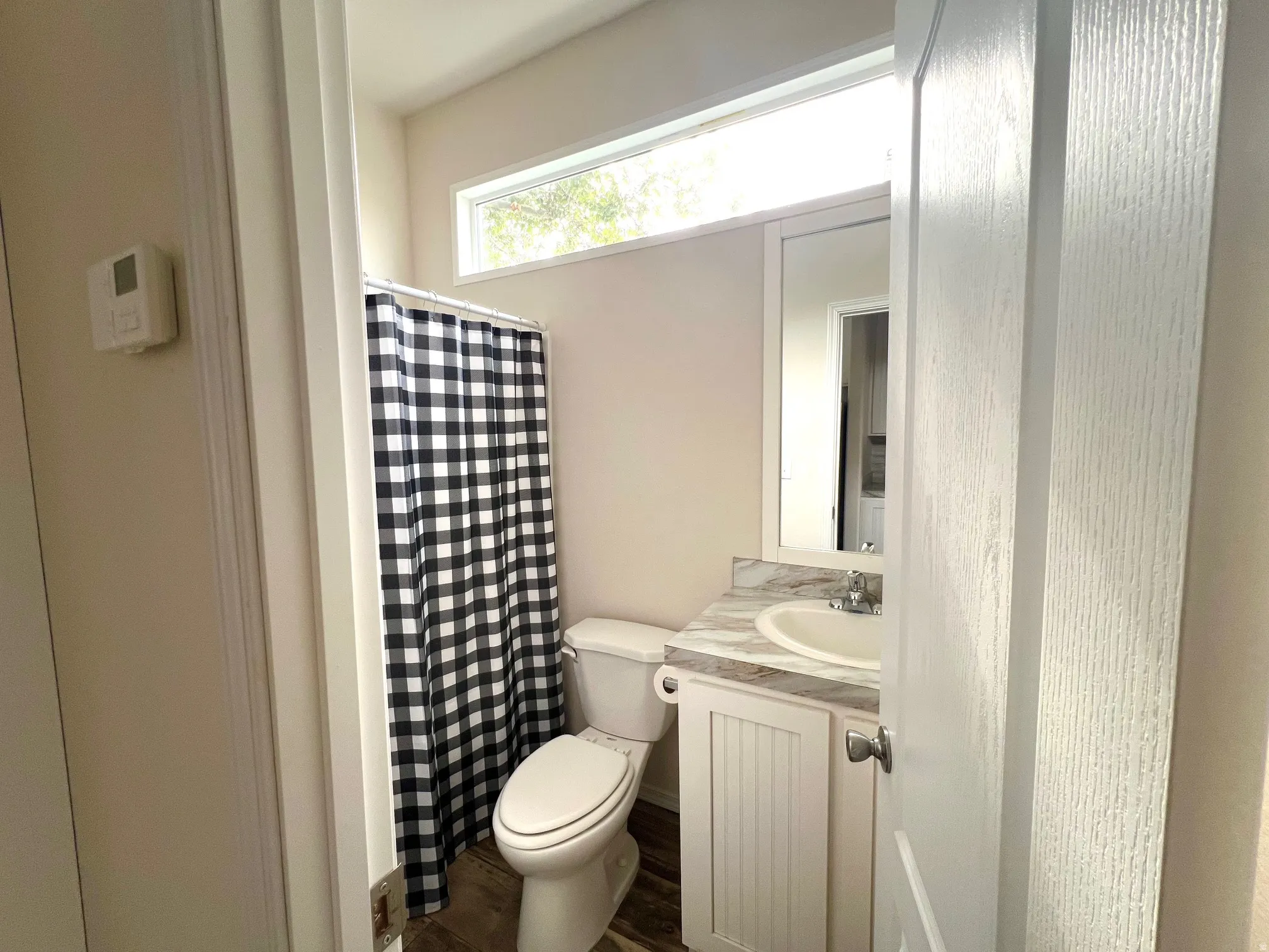Bathroom featuring a white toilet, single vanity with a white basin sink, and a light-toned countertop