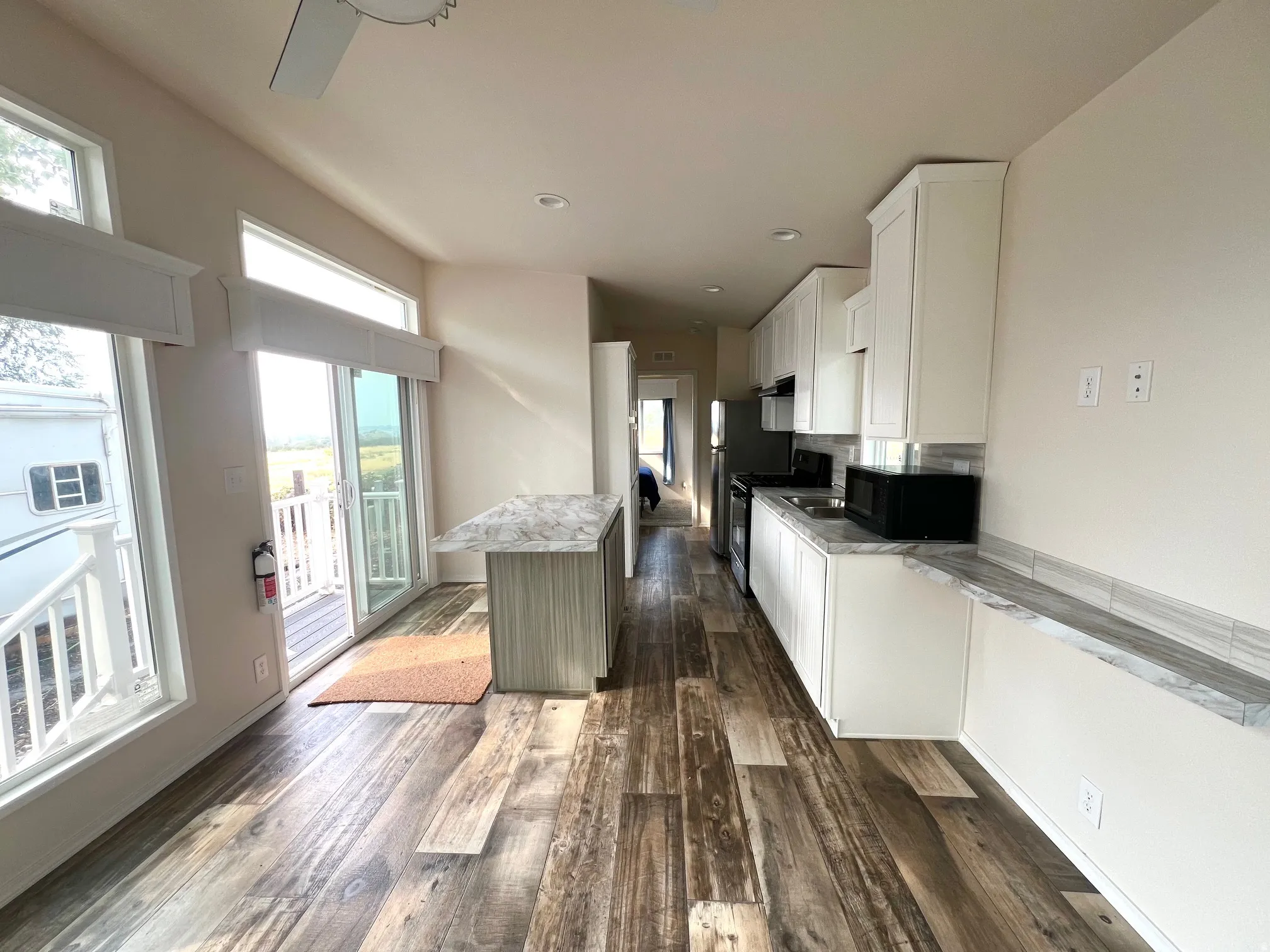 Open-concept kitchen and living area featuring wood-finish flooring, white cabinetry, and light-toned countertops