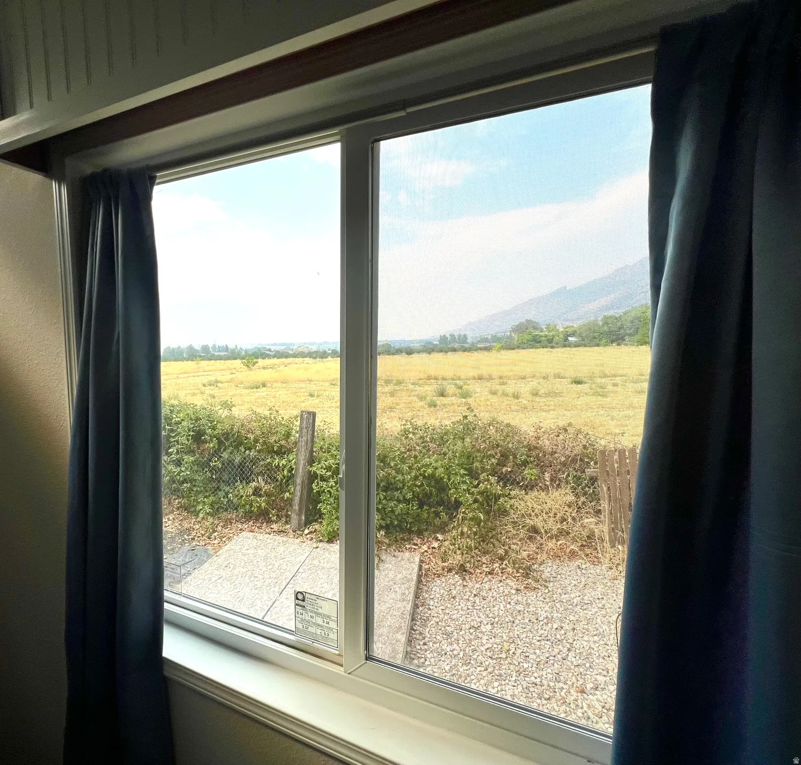 Dual-pane window framing expansive open fields with distant mountains