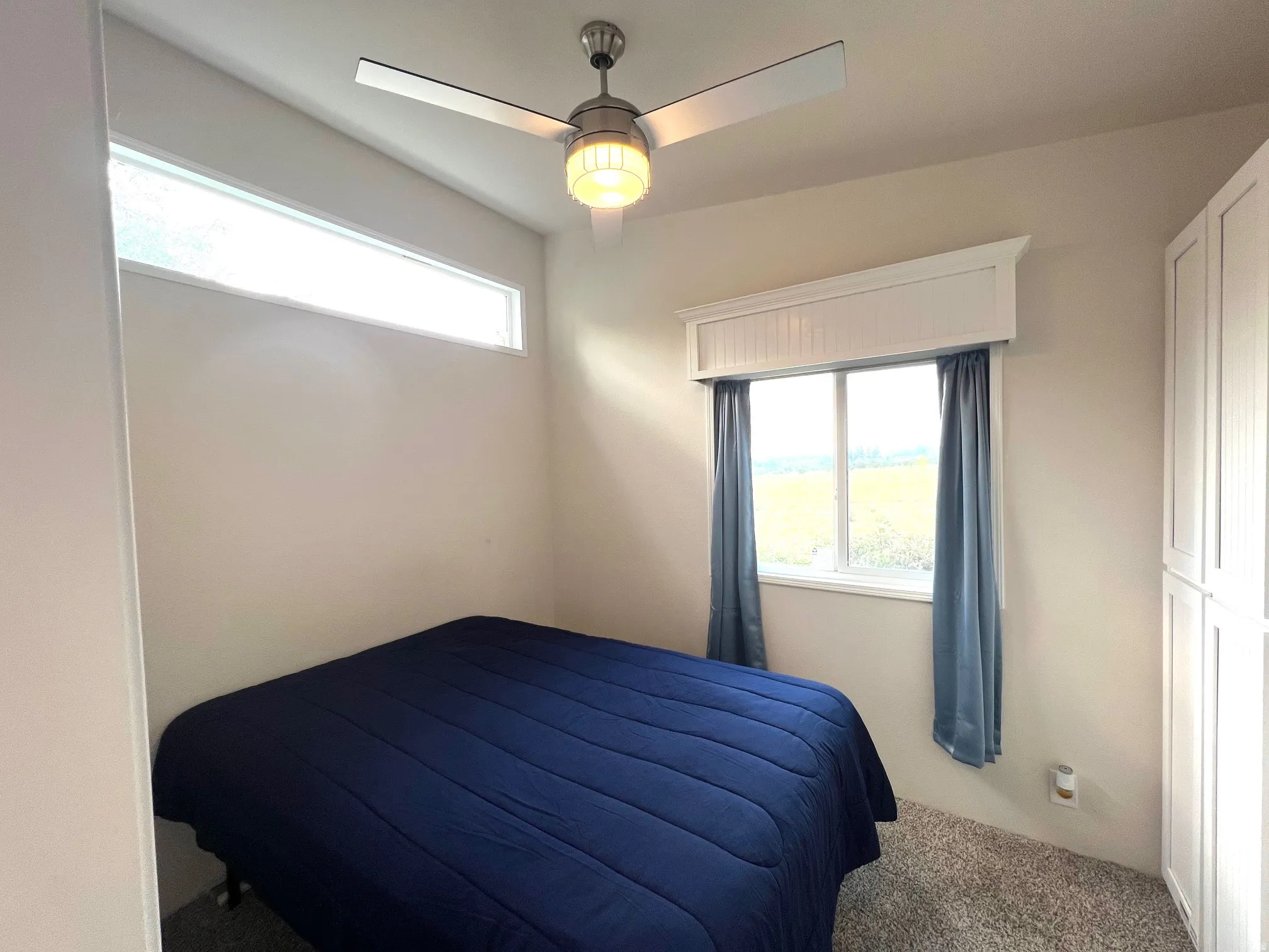 Room featuring light-colored walls, grey carpet, and a ceiling fan with integrated lighting