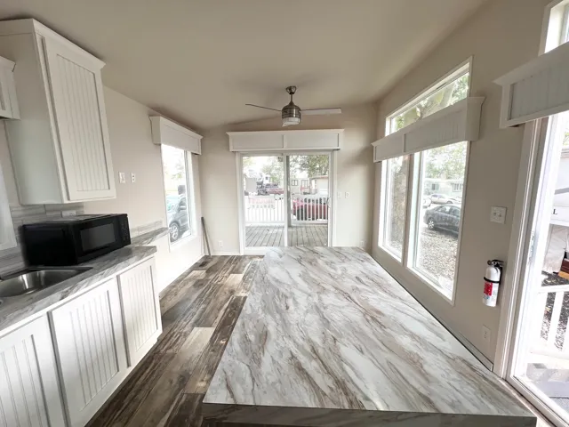 Spacious interior featuring wood-finish flooring, white beadboard cabinetry, and a large central island with a stone-finish countertop