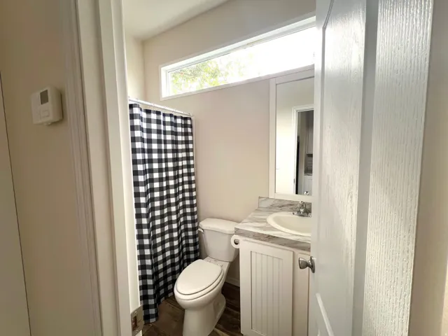 Bathroom featuring a white toilet, single vanity with a white basin sink, and a light-toned countertop