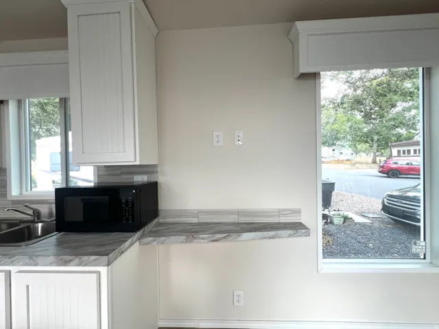Kitchen area featuring white cabinetry, light countertops, and a tiled backsplash