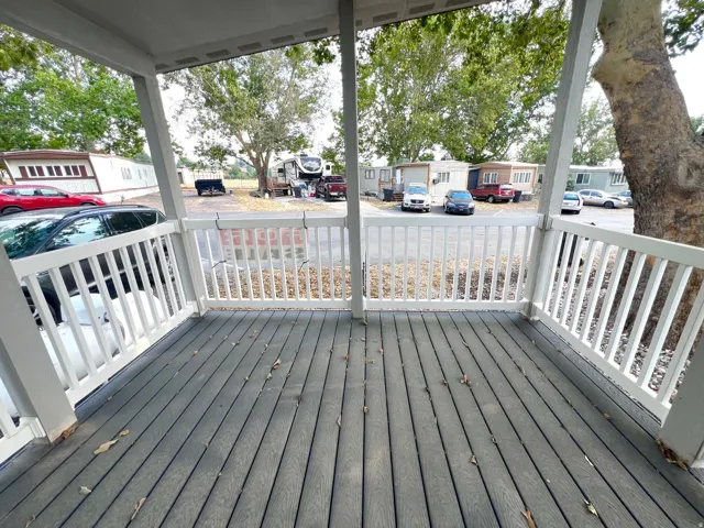 Covered porch featuring wood-finish flooring, white balusters, and a solid railing