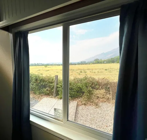 Dual-pane window framing expansive open fields with distant mountains