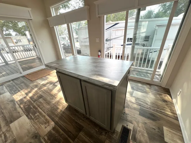 Freestanding kitchen island with a stone-finish countertop and light wood-finish cabinetry