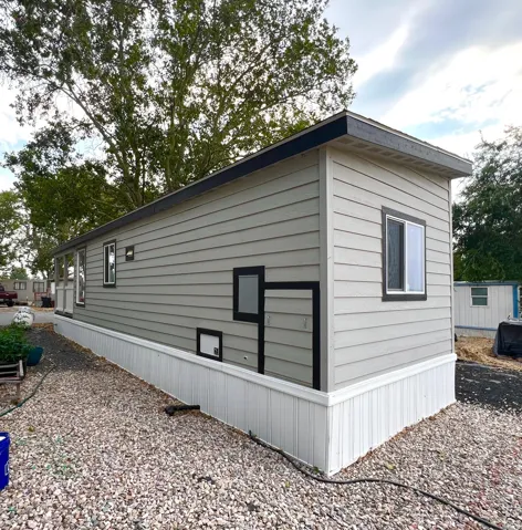 Exterior featuring light grey horizontal siding with dark trim accents