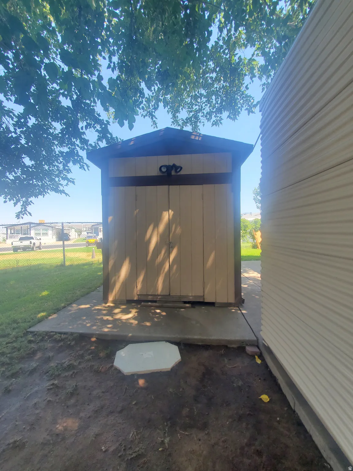 Detached storage shed with a peaked roof, double doors, and a decorative handle, set on a concrete pad