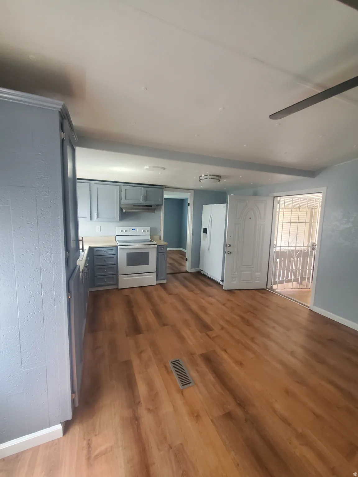 Open concept living area featuring wood-finish flooring, a ceiling fan, and a kitchen with light blue cabinetry