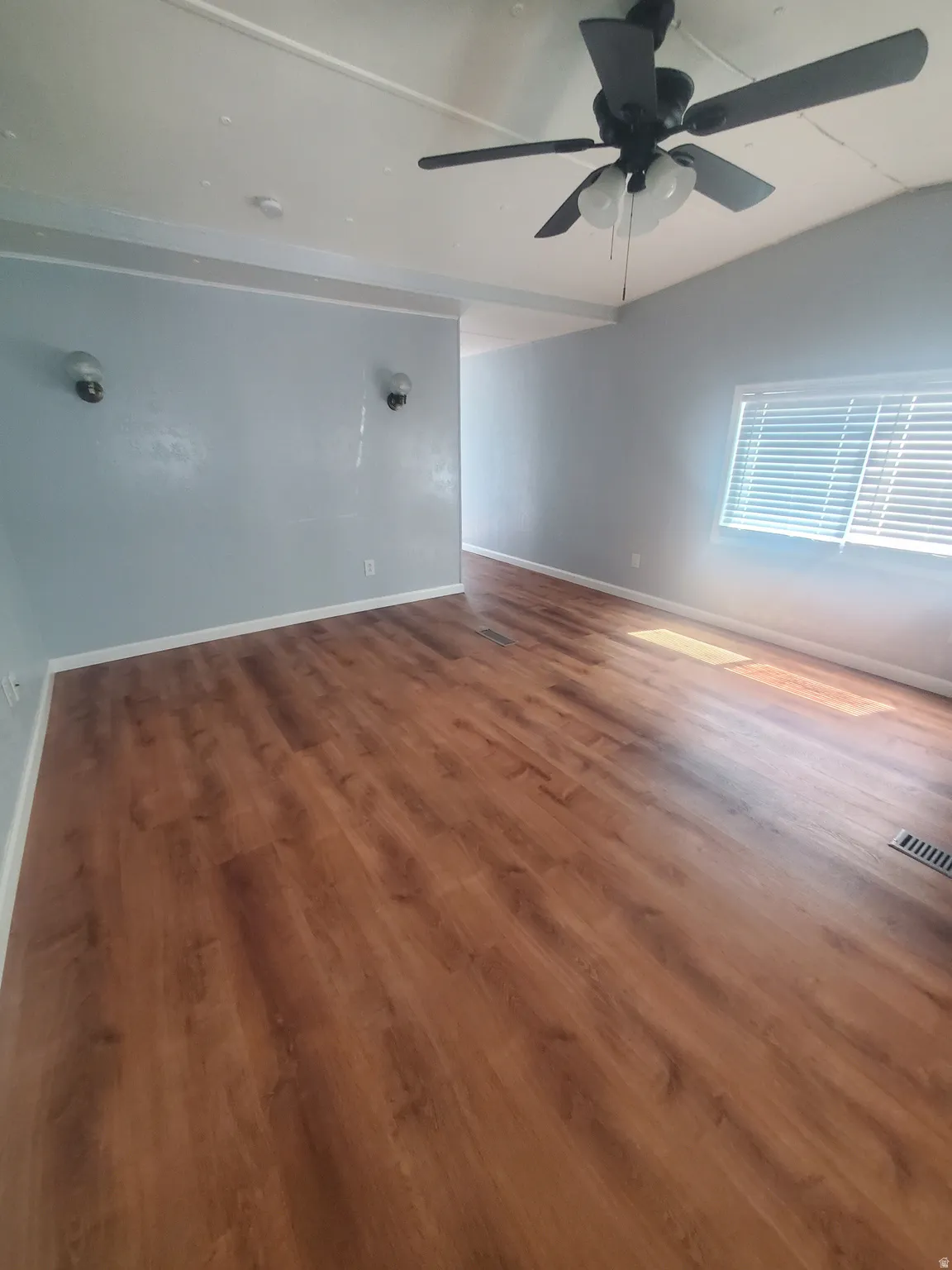 Spacious interior featuring wood-finish flooring, light blue walls, and a ceiling fan with integrated lighting