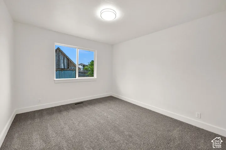 Bright room featuring clean white walls, gray carpet flooring, white trim, a double-pane window, and a flush-mount ceiling light fixture