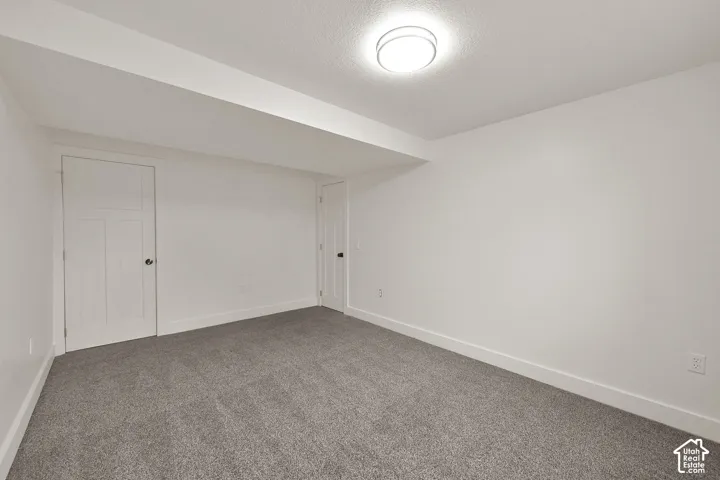 Carpeted room with white walls, baseboards, and two paneled doors