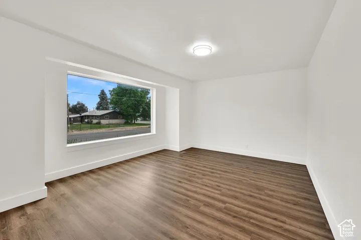 Spacious room featuring wood-finish flooring, white baseboards, and a large horizontal window