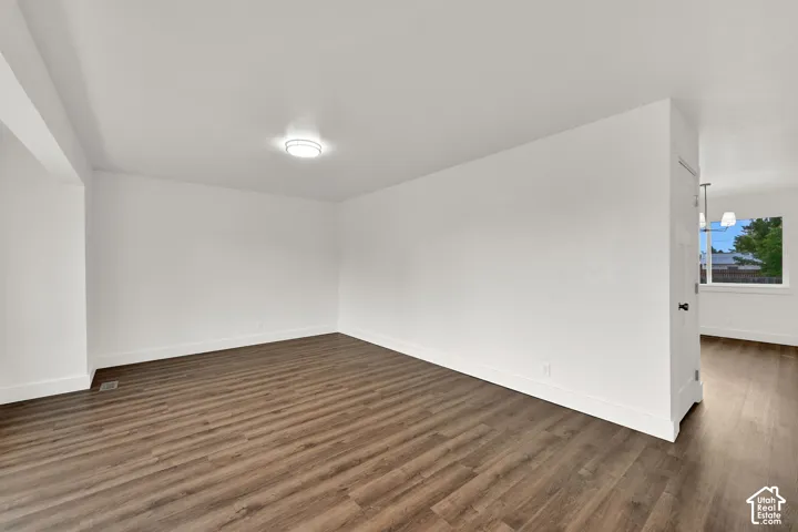 Spacious interior featuring wood-finish flooring, crisp white walls, and a contemporary flush-mount ceiling light