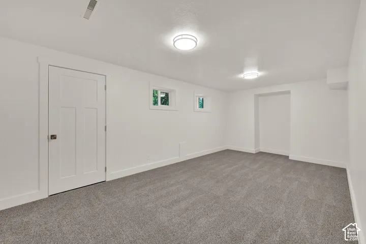 Spacious room featuring neutral carpeting, white walls, and bright overhead lighting