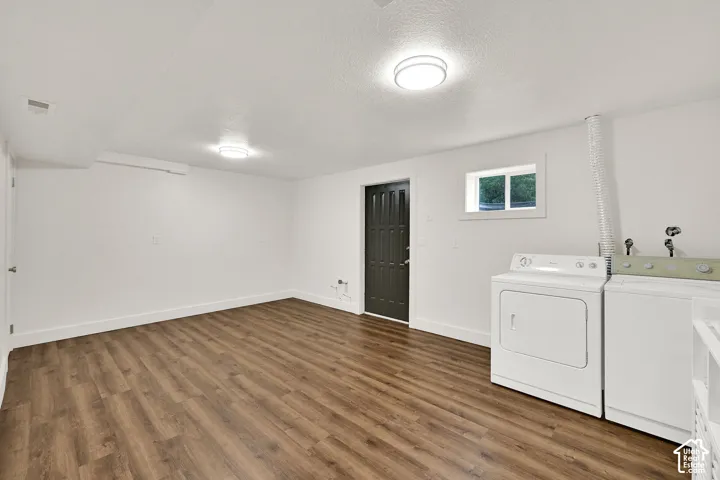 Spacious room featuring wood-finish flooring, white walls, and bright ceiling lighting