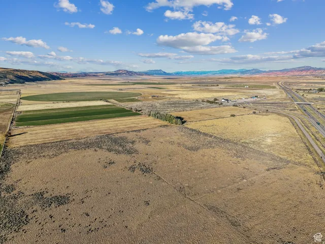 Expansive undeveloped land featuring varied terrain, cultivated fields, and distant mountain ranges