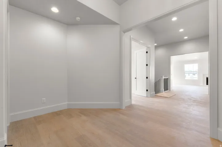 Recessed lighting illuminates wood-finish flooring and crisp white walls