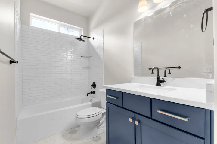 Bathroom featuring a single vanity with a blue cabinet, a white countertop, and a matte black faucet