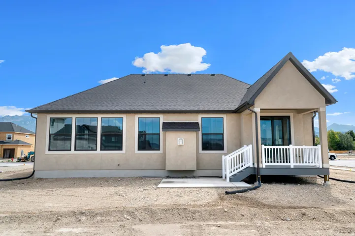 Rear exterior featuring a covered porch with white railing, a sliding glass door, and multiple large windows
