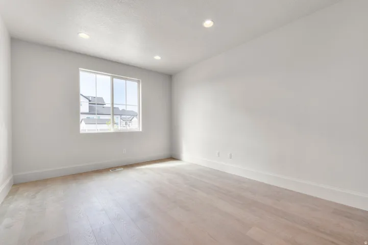 Bright interior space featuring a large multi-pane window, recessed lighting, light wood-finish flooring, and white trim throughout
