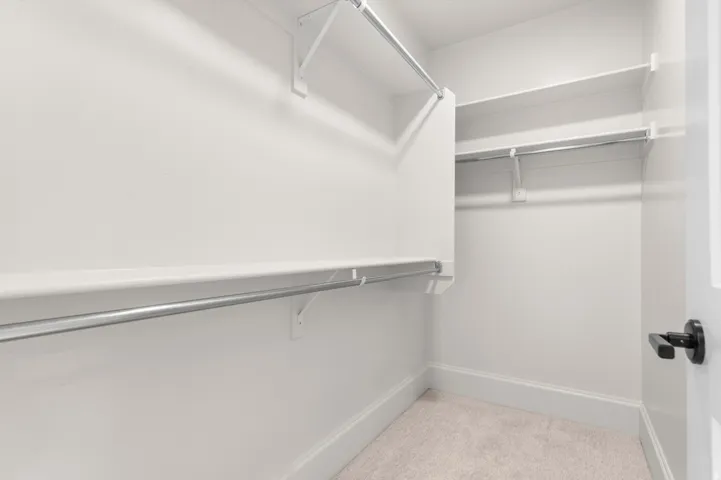 Walk-in closet featuring white shelving and chrome hanging rods