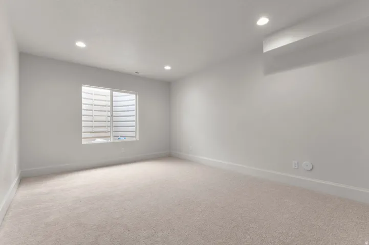 Carpeted room with recessed lighting and a window featuring a window well
