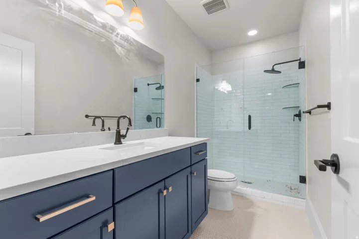 Bathroom featuring a large vanity with a white countertop and blue cabinetry, a rectangular undermount sink, and a dark bronze faucet