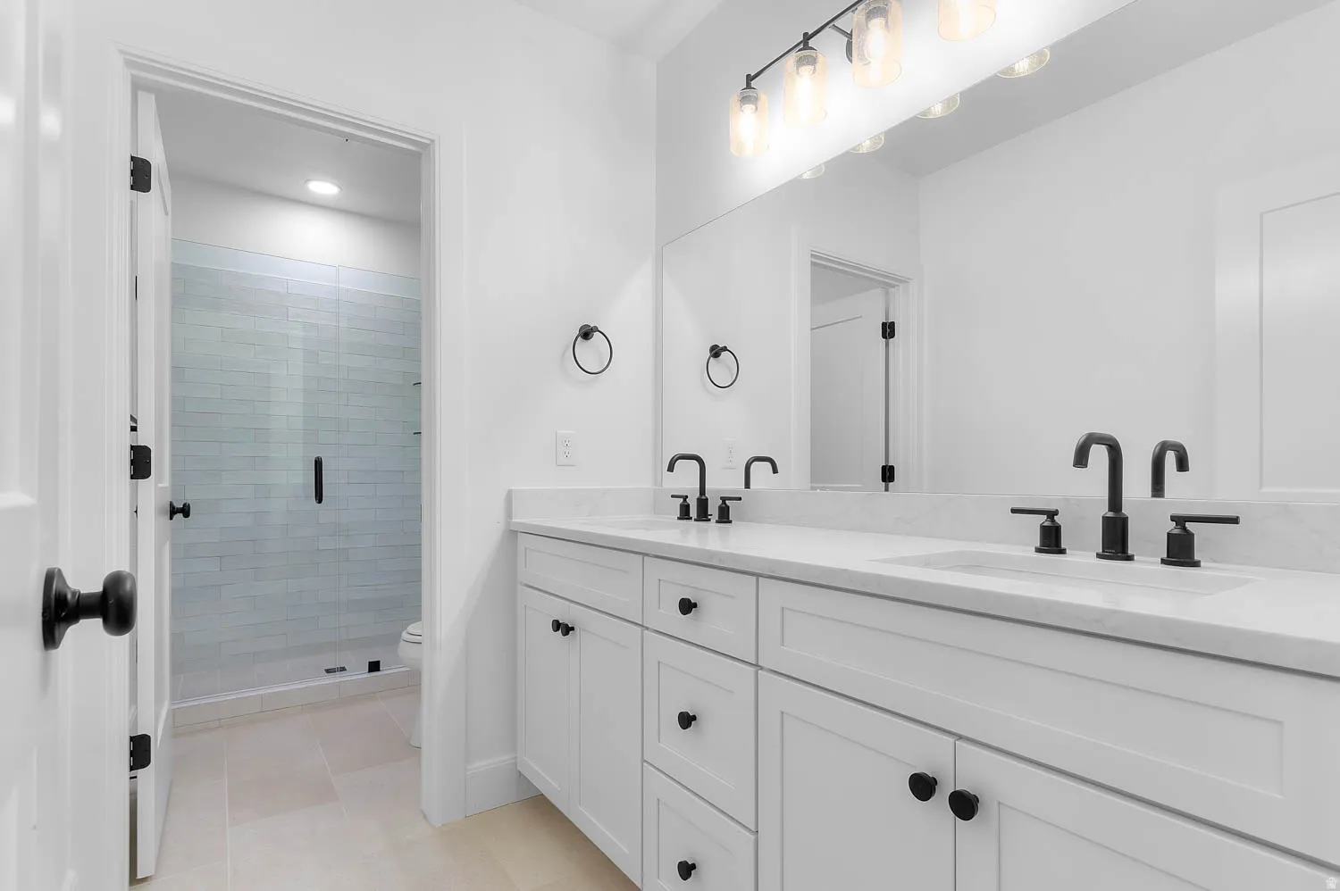 Double vanity with stone countertop and integrated sinks, featuring matte black faucets and hardware