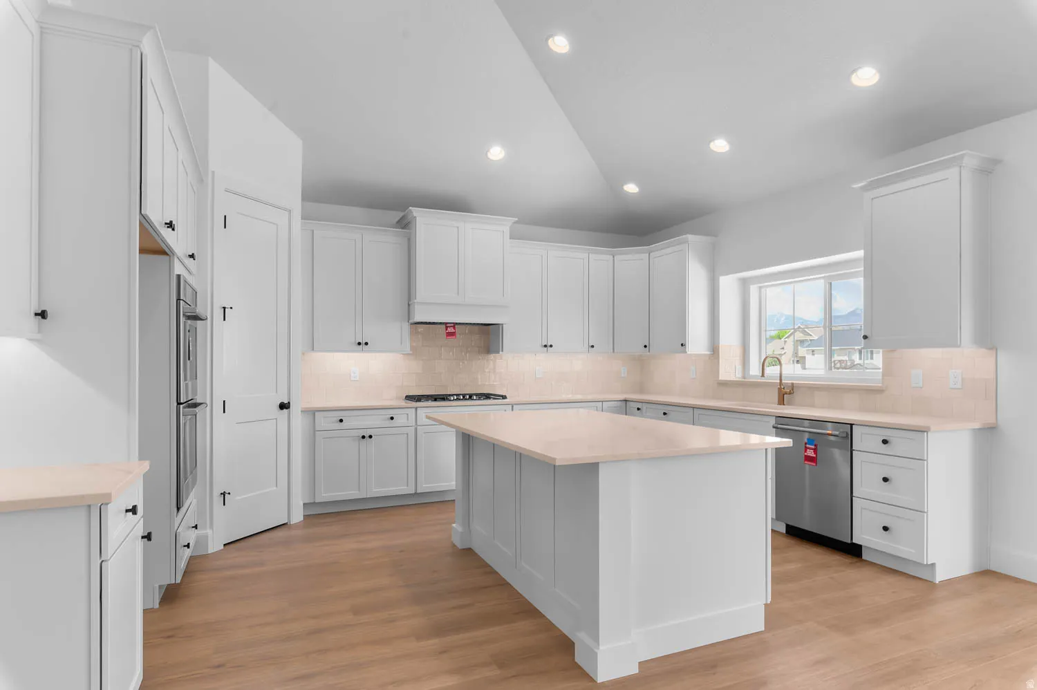 Spacious kitchen featuring white cabinetry, light countertops, wood-finish flooring, and recessed lighting