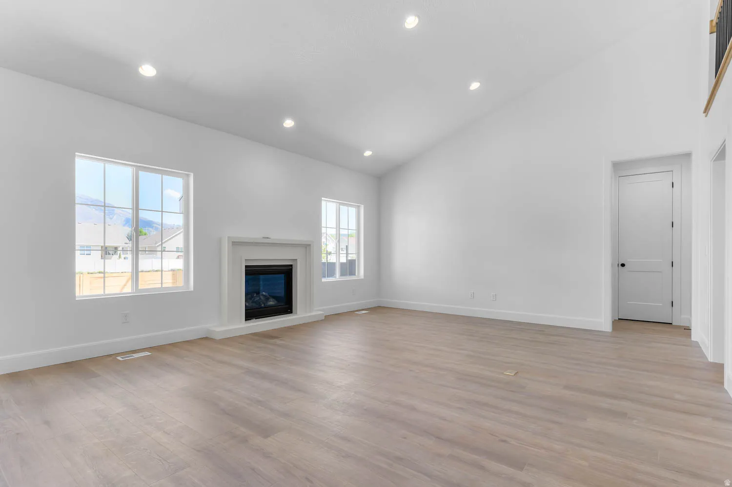 Expansive living space featuring wood-finish flooring and a white fireplace with a decorative mantel