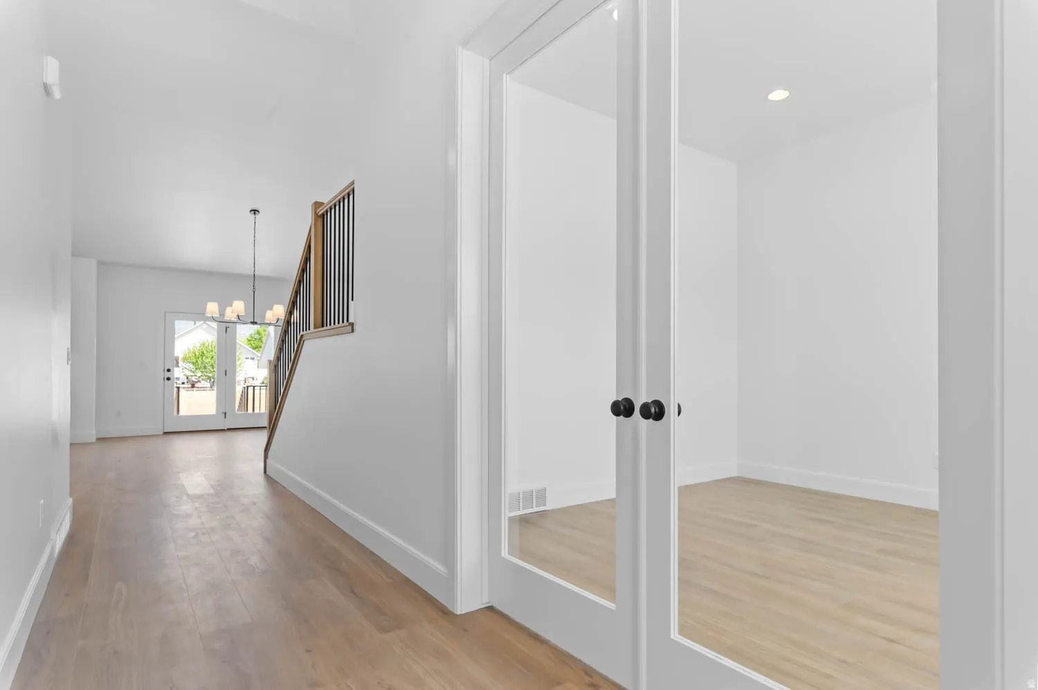 French doors featuring matte black hardware opening to a versatile room with recessed lighting