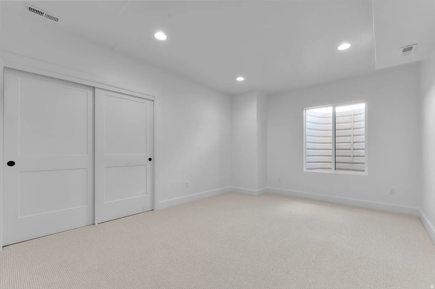 Spacious room featuring neutral carpeting and white walls
