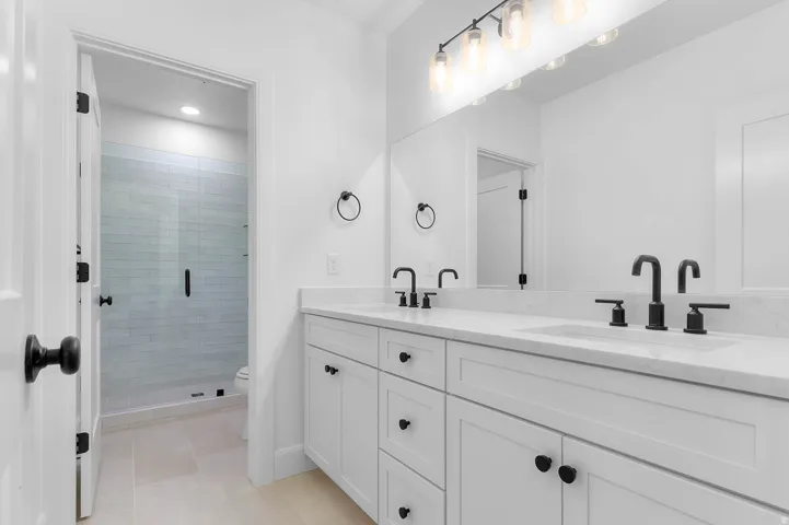 Double vanity with stone countertop and integrated sinks, featuring matte black faucets and hardware