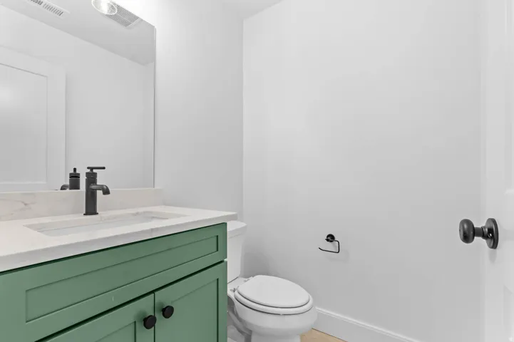 Powder room featuring a green vanity with a light-colored countertop, an undermount sink, and a matte black faucet