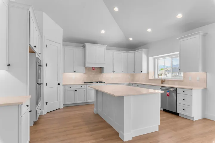 Spacious kitchen featuring white cabinetry, light countertops, wood-finish flooring, and recessed lighting