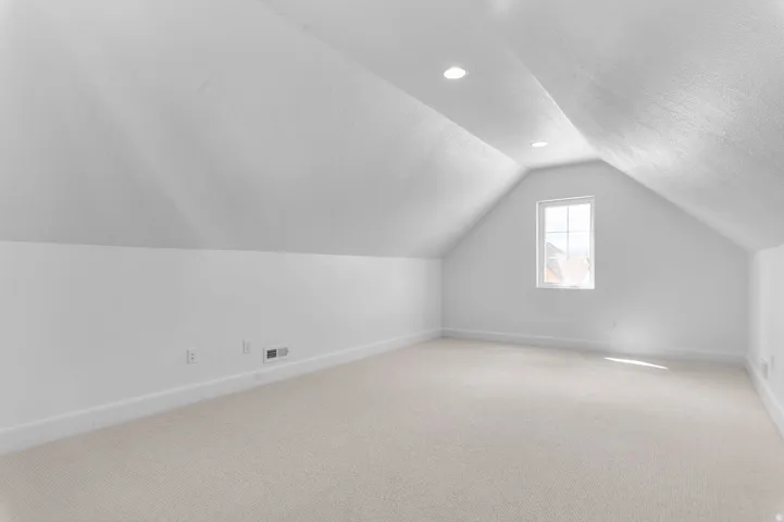 Carpeted room featuring an attic ceiling with recessed lighting