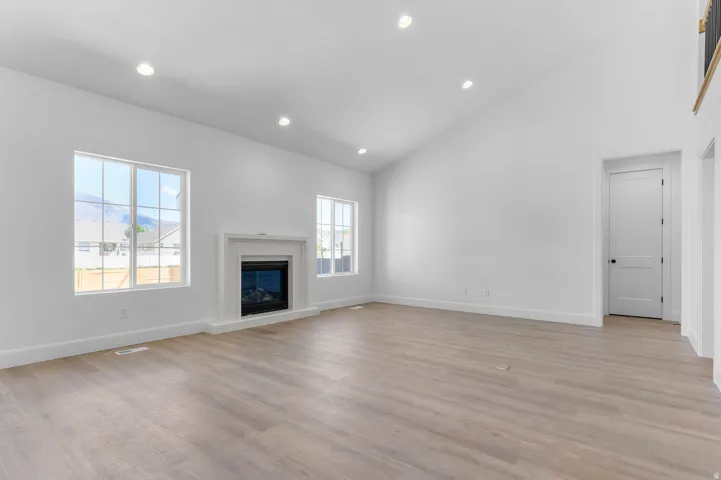 Expansive living space featuring wood-finish flooring and a white fireplace with a decorative mantel