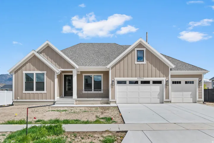 Contemporary ranch-style residence featuring a prominent two-car garage with overhead lighting
