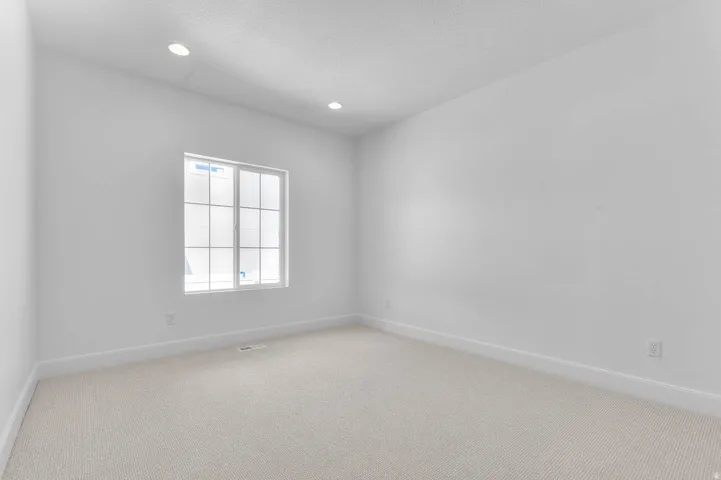 Bright room featuring a grid-patterned window, recessed lighting, neutral carpet, and white baseboards