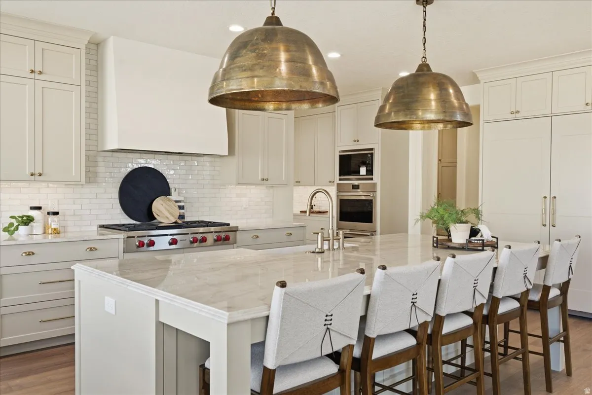 Gourmet kitchen featuring a substantial island with seating, a professional-grade range, a custom vent hood, and dual pendant light fixtures