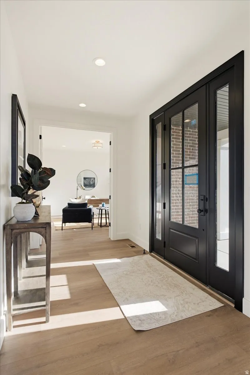 Entryway featuring wood-finish flooring, recessed lighting, and a black double-door entry with glass panels
