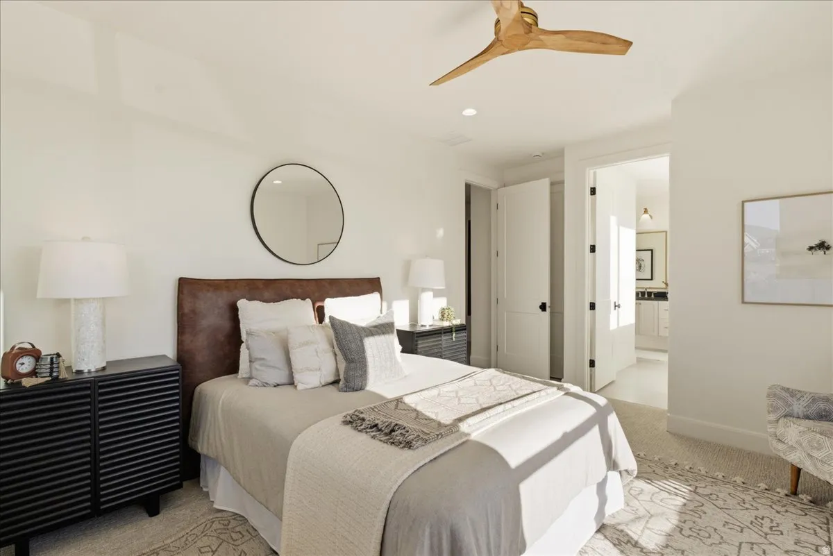 Bedroom featuring light-toned walls, a decorative ceiling fan, and carpeted flooring