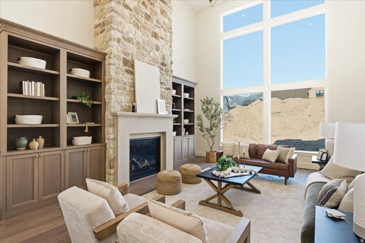 Expansive living area featuring a floor-to-ceiling stone fireplace, built-in shelving and cabinetry, and a full wall of tall windows