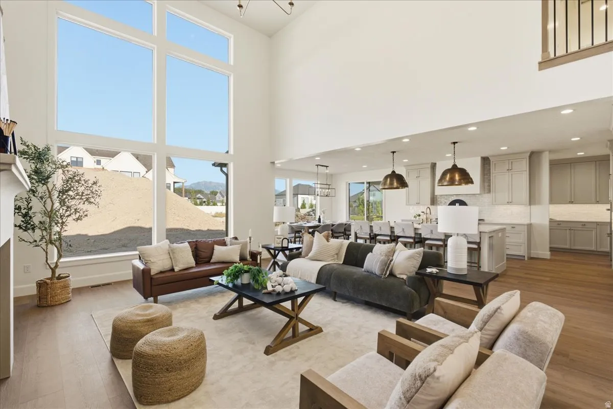 Two-story living area with expansive windows, wood-finish flooring, and recessed lighting