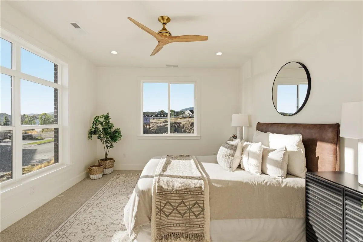 Carpeted bedroom with a wood-tone ceiling fan, recessed lighting, and white walls